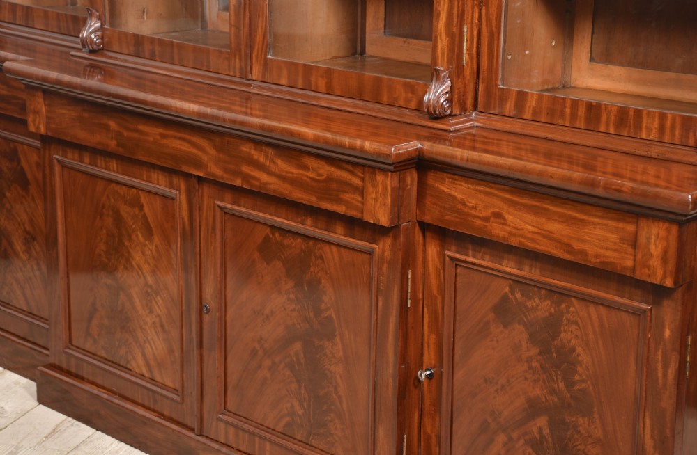 A 19th-century mahogany breakfront bookcase featuring glazed upper doors with adjustable shelves above a base with flame mahogany panelled doors. View XIV