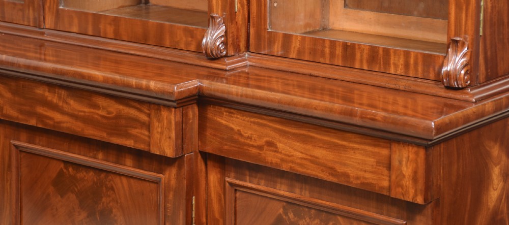 A 19th-century mahogany breakfront bookcase featuring glazed upper doors with adjustable shelves above a base with flame mahogany panelled doors. View XVI