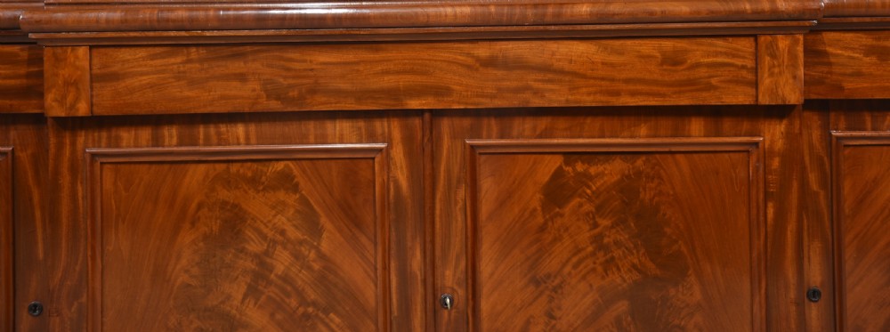 A 19th-century mahogany breakfront bookcase featuring glazed upper doors with adjustable shelves above a base with flame mahogany panelled doors. View XX