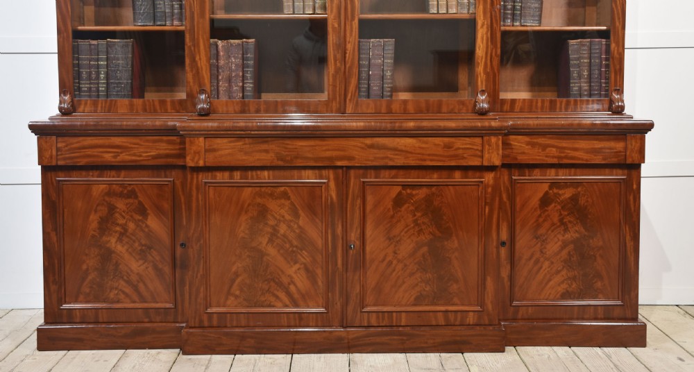 A 19th-century mahogany breakfront bookcase featuring glazed upper doors with adjustable shelves above a base with flame mahogany panelled doors. View XXI
