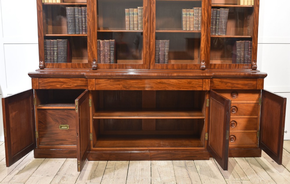 A 19th-century mahogany breakfront bookcase featuring glazed upper doors with adjustable shelves above a base with flame mahogany panelled doors. View XXIII