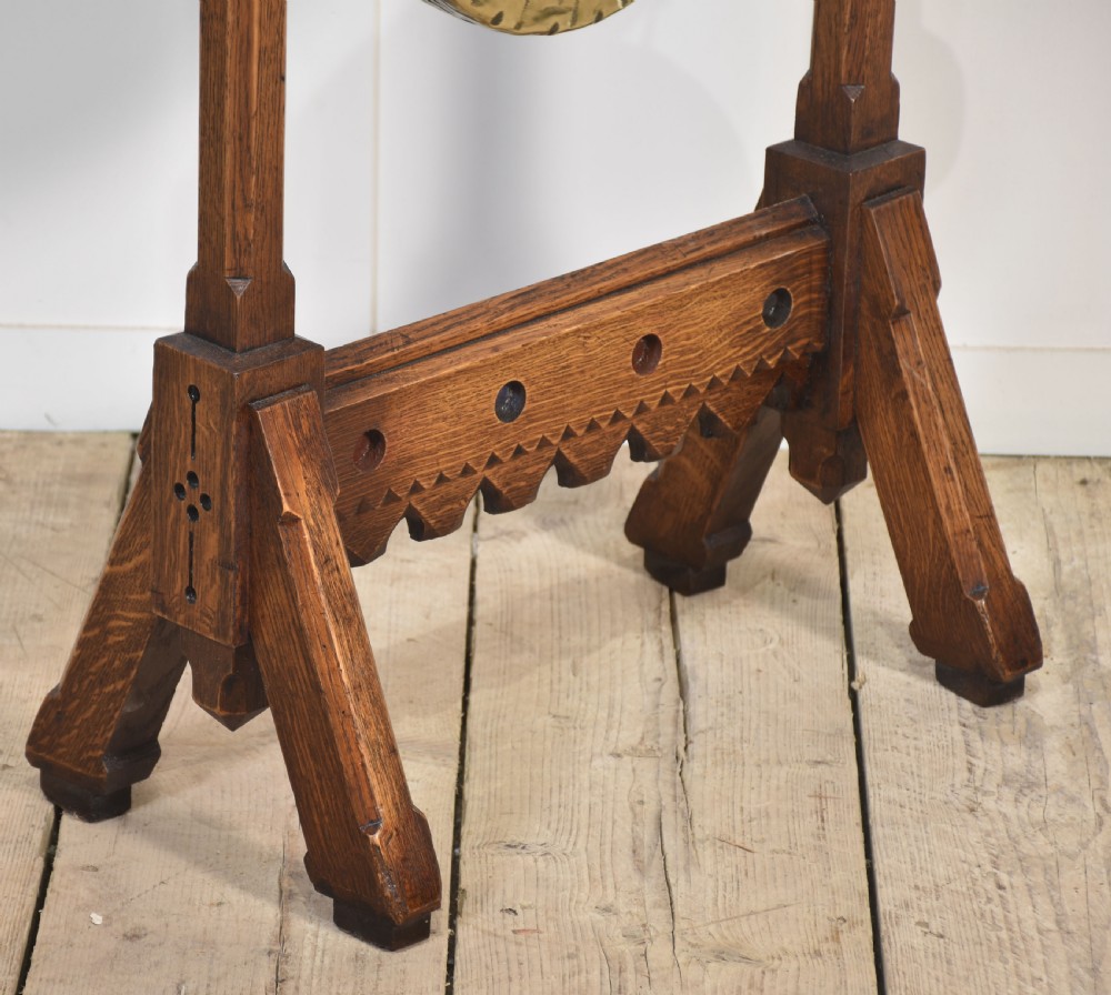 A carved oak freestanding frame in Gothic Revival style housing a central suspended circular brass gong with an attached wooden striker. View IV