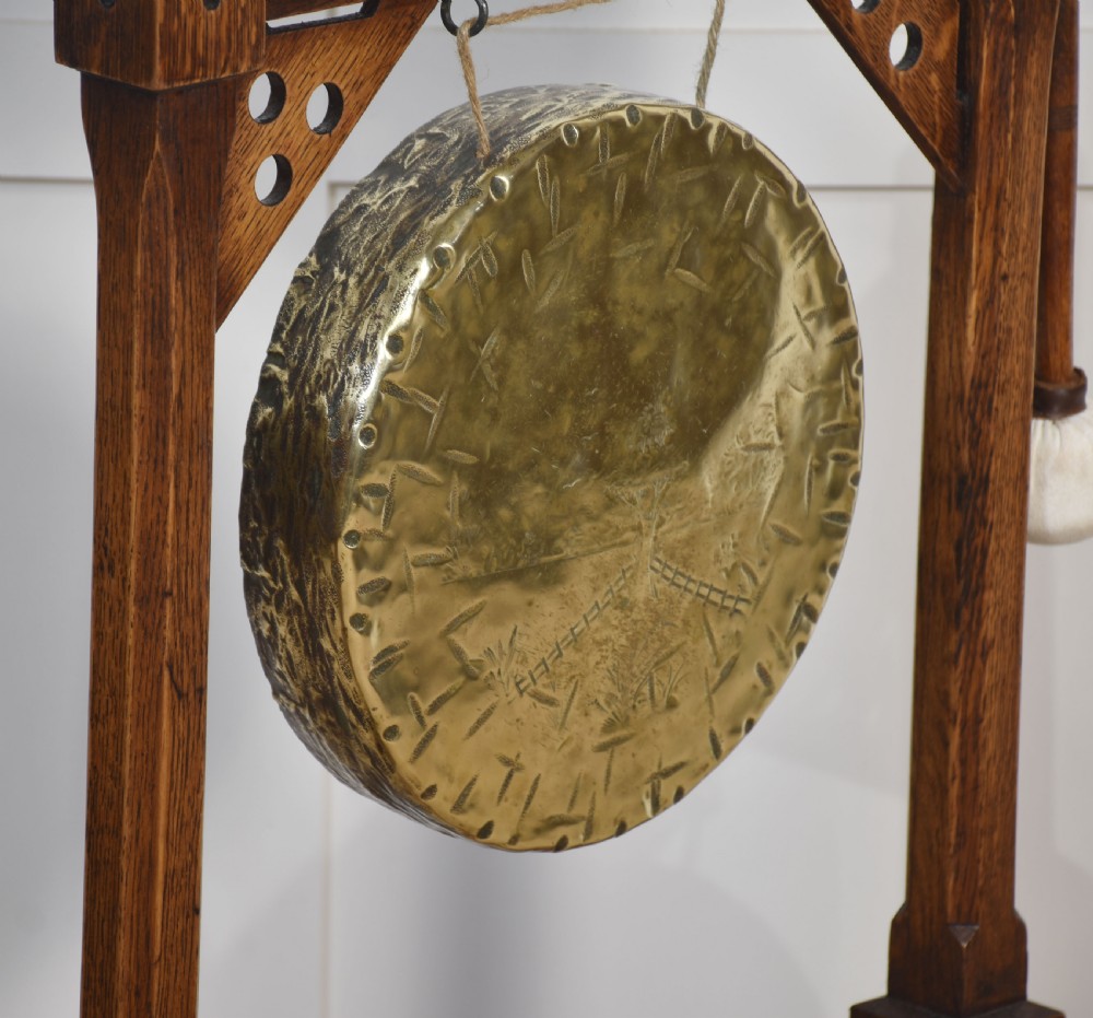 A carved oak freestanding frame in Gothic Revival style housing a central suspended circular brass gong with an attached wooden striker. View VIII