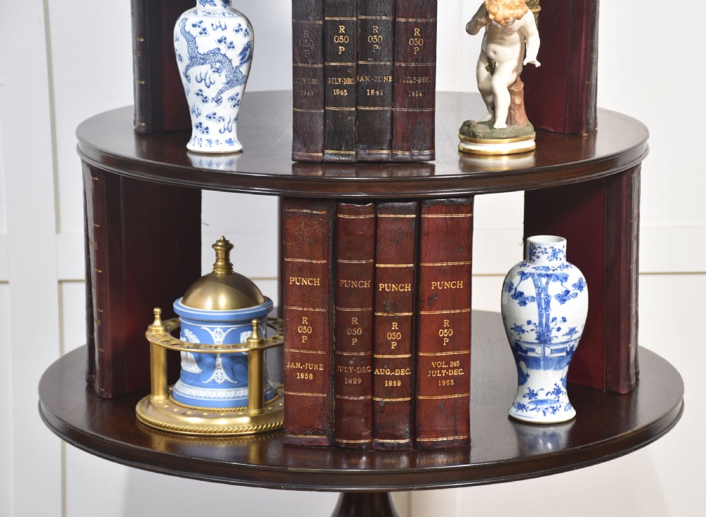 A four-tiered mahogany revolving bookcase featuring a top finial, graduated open circular shelves, and a pedestal tripod base on brass castors. View V