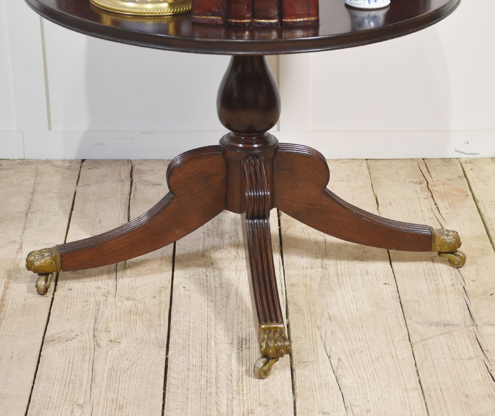 A four-tiered mahogany revolving bookcase featuring a top finial, graduated open circular shelves, and a pedestal tripod base on brass castors. View VI