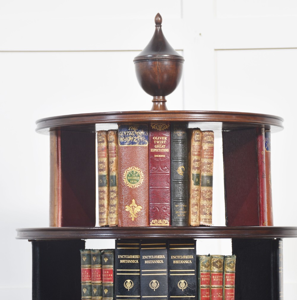 A four-tiered mahogany revolving bookcase featuring a top finial, graduated open circular shelves, and a pedestal tripod base on brass castors. View VII