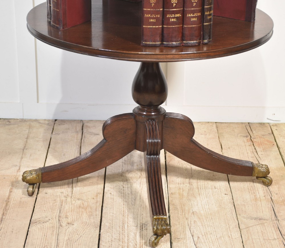 A four-tiered mahogany revolving bookcase featuring a top finial, graduated open circular shelves, and a pedestal tripod base on brass castors. View X