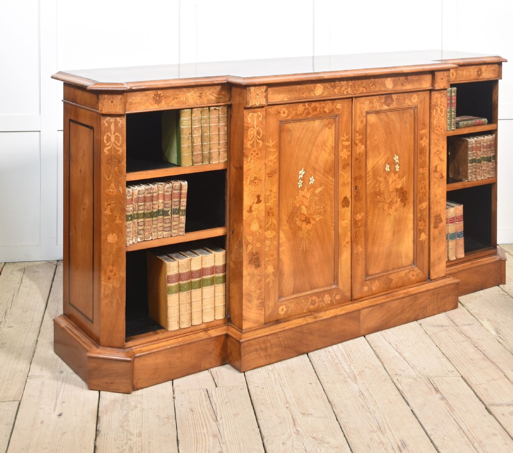 A low antique walnut breakfront bookcase featuring floral marquetry inlay across the central cupboard doors and top frieze, flanked by open adjustable shelves. View V