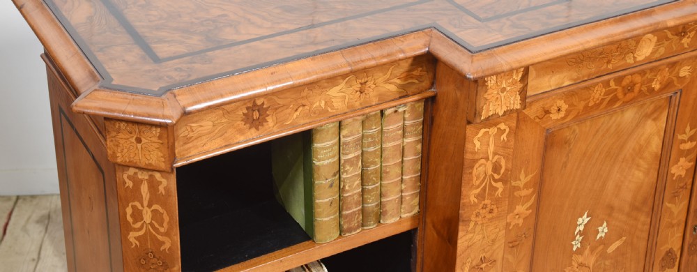 A low antique walnut breakfront bookcase featuring floral marquetry inlay across the central cupboard doors and top frieze, flanked by open adjustable shelves. View X