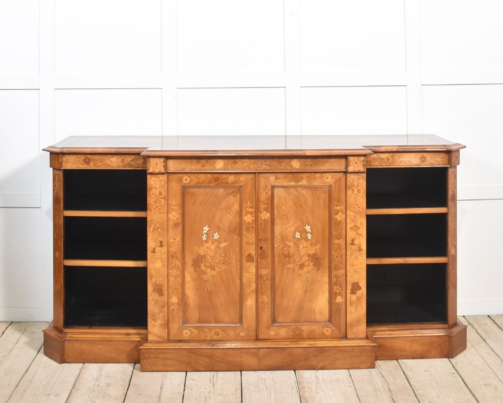 A low antique walnut breakfront bookcase featuring floral marquetry inlay across the central cupboard doors and top frieze, flanked by open adjustable shelves. View XI