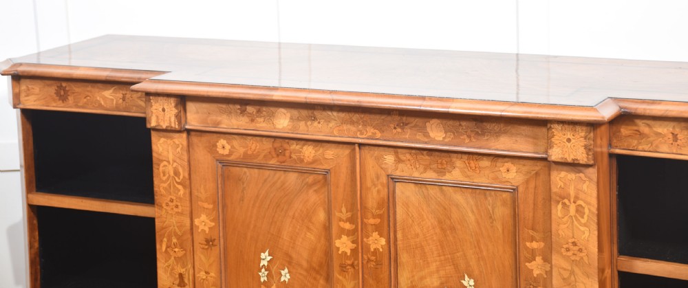 A low antique walnut breakfront bookcase featuring floral marquetry inlay across the central cupboard doors and top frieze, flanked by open adjustable shelves. View XIII