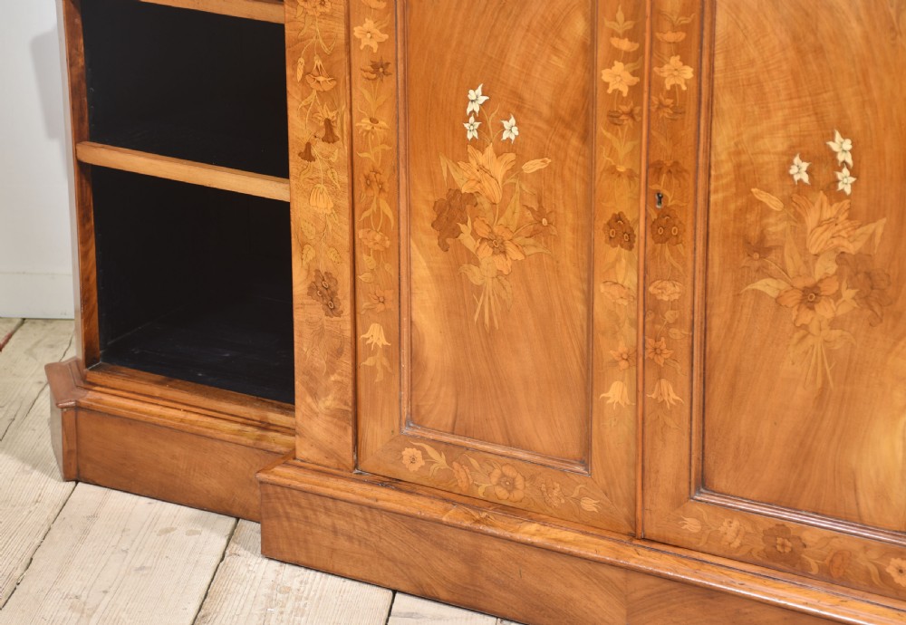 A low antique walnut breakfront bookcase featuring floral marquetry inlay across the central cupboard doors and top frieze, flanked by open adjustable shelves. View XV