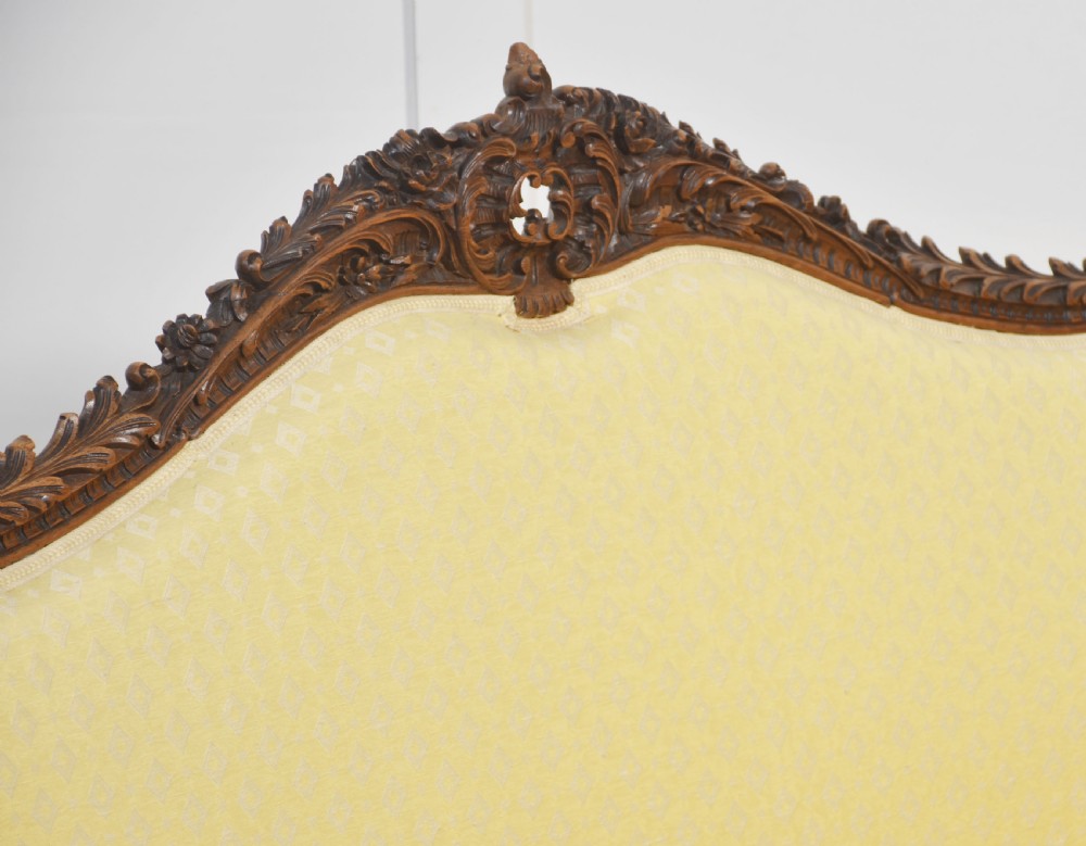 An antique carved walnut two-seater settee featuring patterned yellow upholstery, curved arms, and cabriole legs. View II