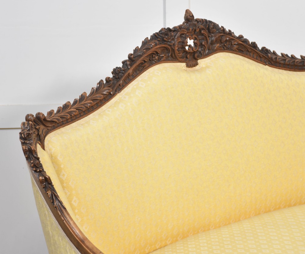 An antique carved walnut two-seater settee featuring patterned yellow upholstery, curved arms, and cabriole legs. View VI