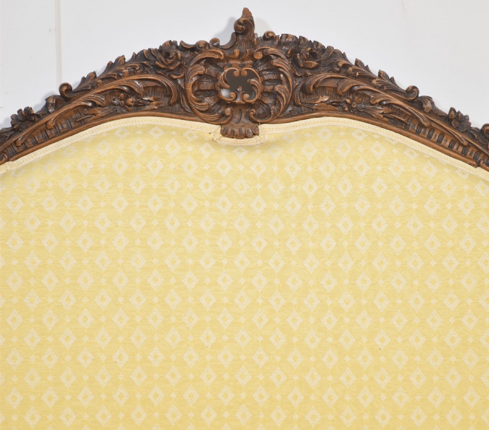 An antique carved walnut two-seater settee featuring patterned yellow upholstery, curved arms, and cabriole legs. View VIII