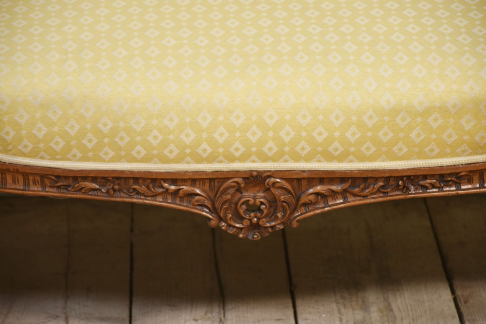An antique carved walnut two-seater settee featuring patterned yellow upholstery, curved arms, and cabriole legs. View IX