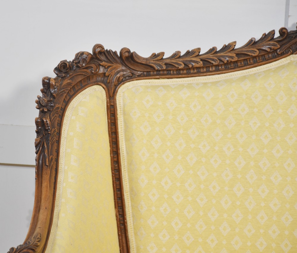 An antique carved walnut two-seater settee featuring patterned yellow upholstery, curved arms, and cabriole legs. View X