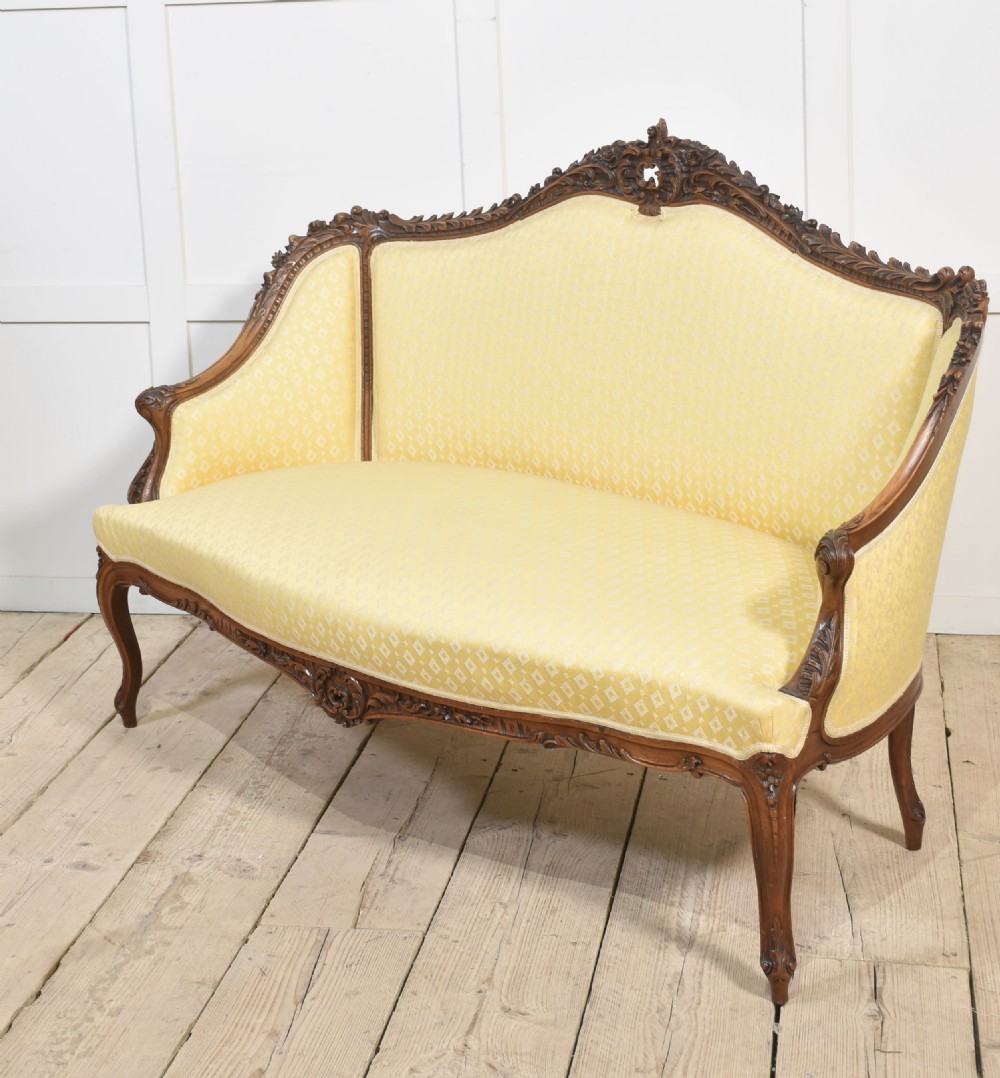 An antique carved walnut two-seater settee featuring patterned yellow upholstery, curved arms, and cabriole legs. View XII