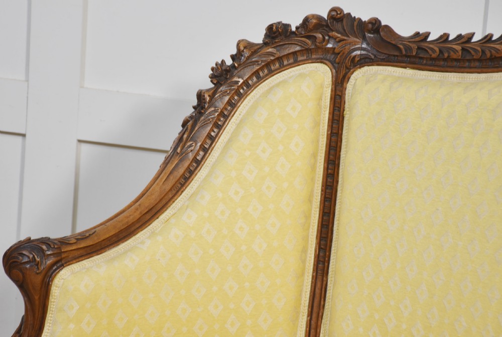 An antique carved walnut two-seater settee featuring patterned yellow upholstery, curved arms, and cabriole legs. View XIV