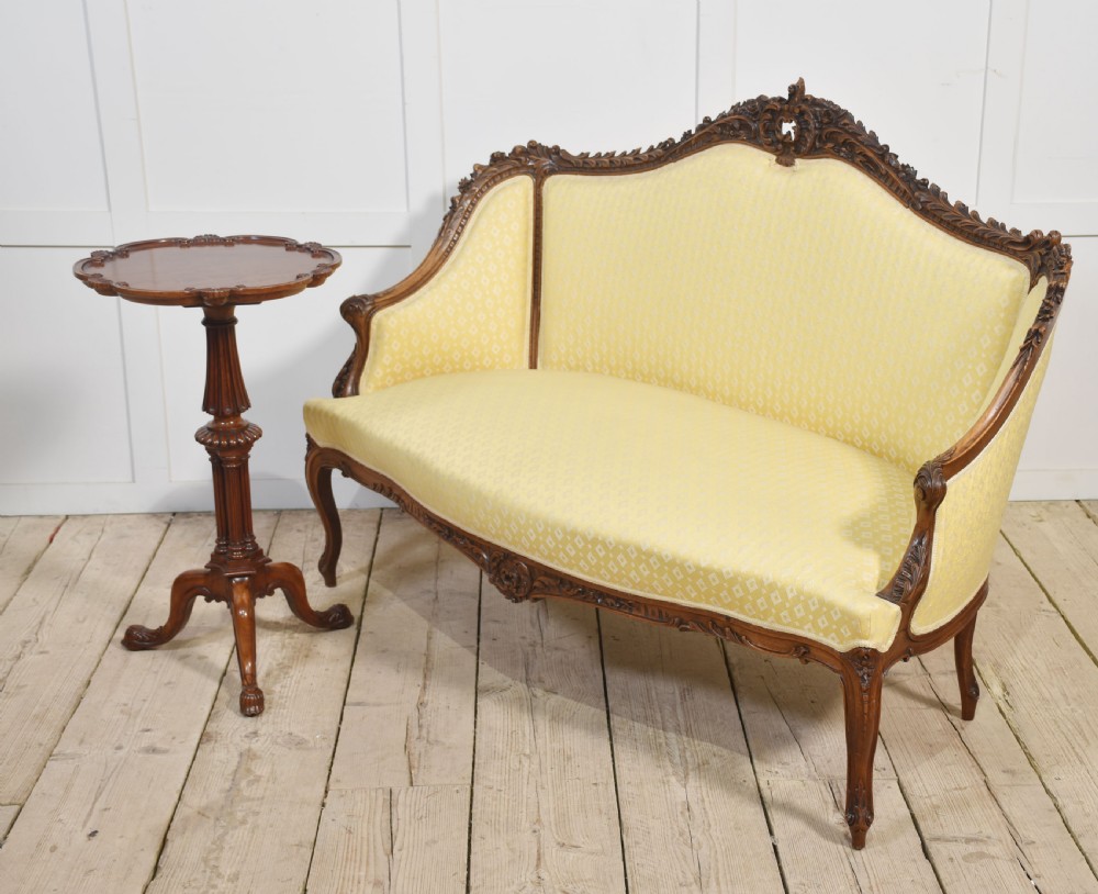 An antique carved walnut two-seater settee featuring patterned yellow upholstery, curved arms, and cabriole legs. View XVI