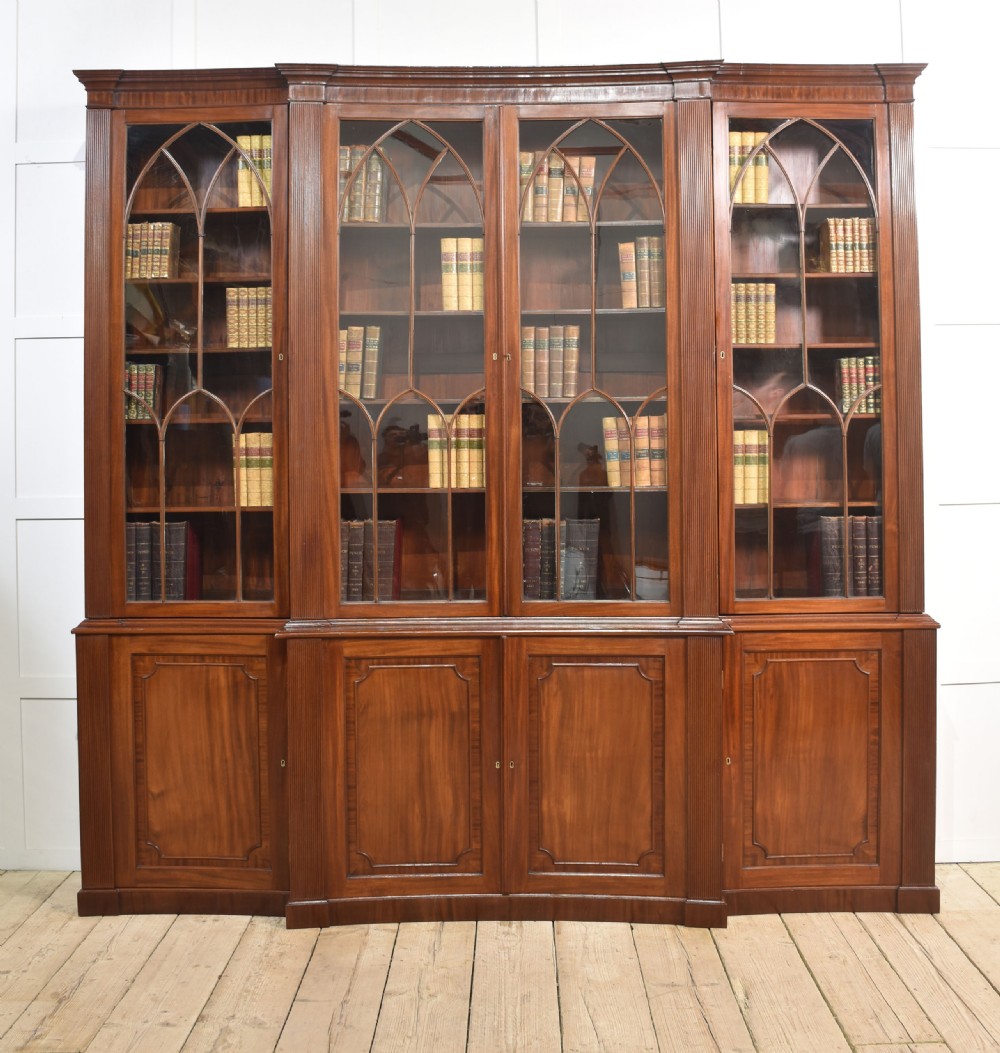 A large Regency mahogany breakfront library bookcase featuring four astragal glazed doors with Gothic arch detailing over four panelled cupboard bases.