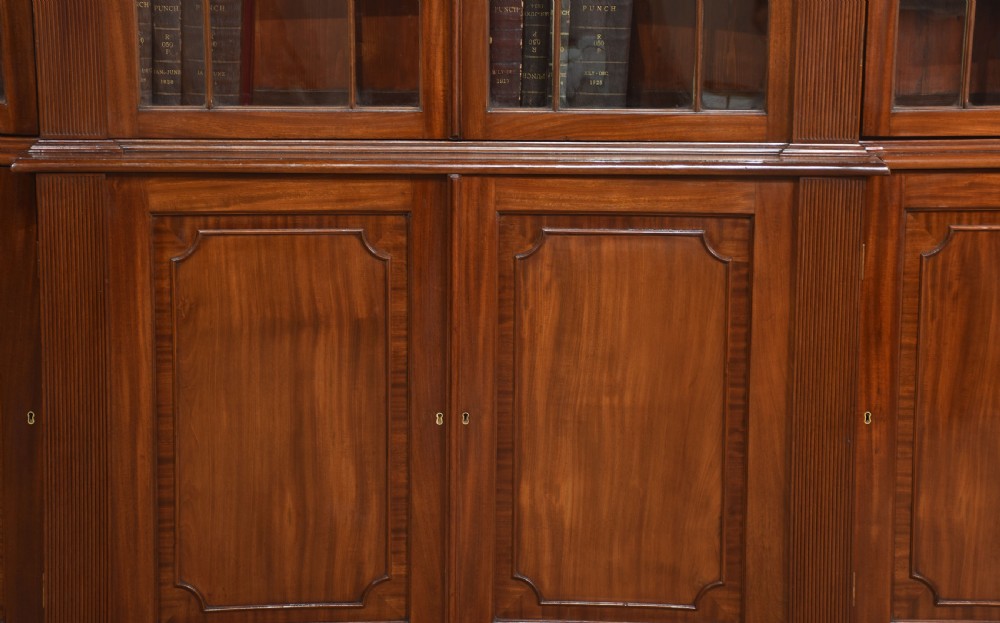 A large Regency mahogany breakfront library bookcase featuring four astragal glazed doors with Gothic arch detailing over four panelled cupboard bases. View V