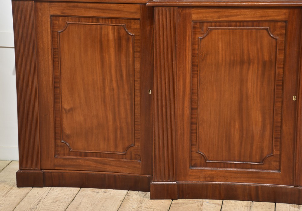 A large Regency mahogany breakfront library bookcase featuring four astragal glazed doors with Gothic arch detailing over four panelled cupboard bases. View VI