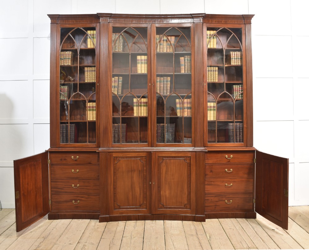 A large Regency mahogany breakfront library bookcase featuring four astragal glazed doors with Gothic arch detailing over four panelled cupboard bases. View VII