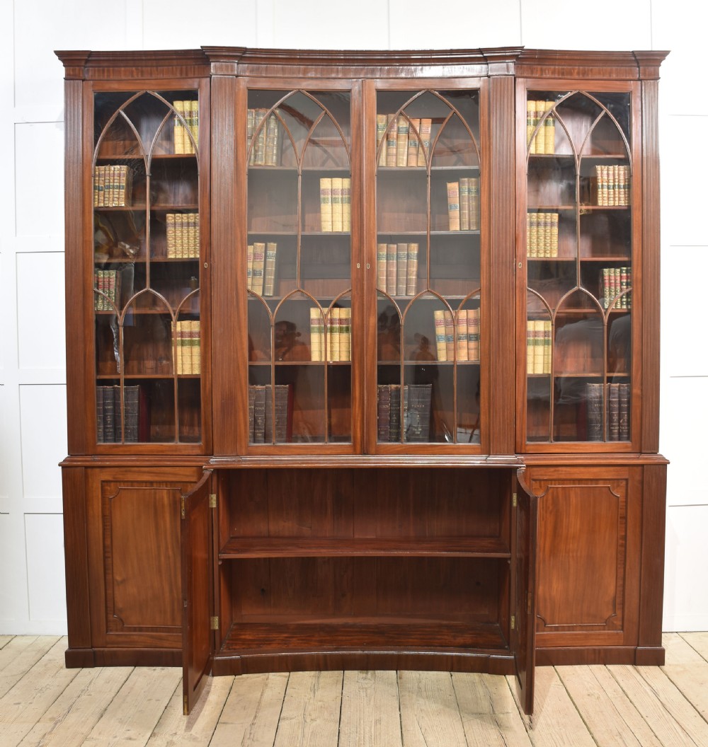 A large Regency mahogany breakfront library bookcase featuring four astragal glazed doors with Gothic arch detailing over four panelled cupboard bases. View IX