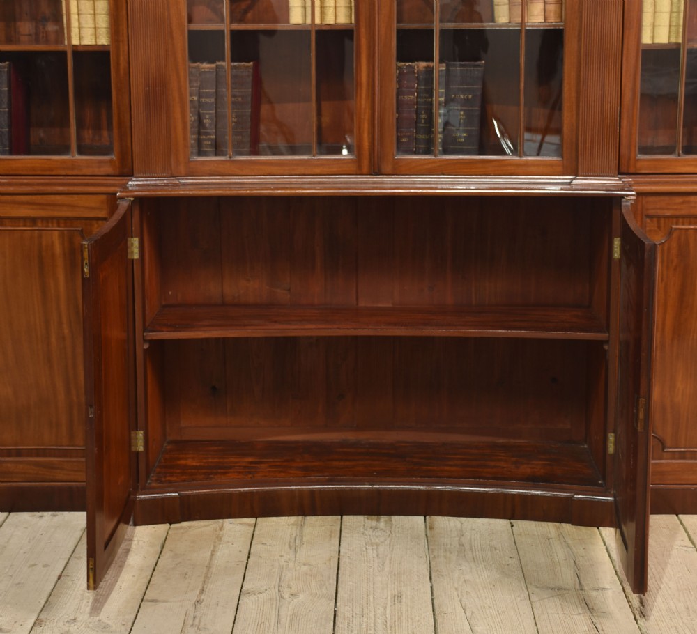 A large Regency mahogany breakfront library bookcase featuring four astragal glazed doors with Gothic arch detailing over four panelled cupboard bases. View X