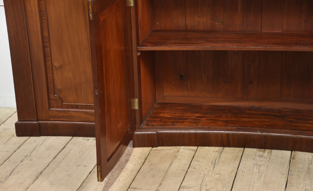 A large Regency mahogany breakfront library bookcase featuring four astragal glazed doors with Gothic arch detailing over four panelled cupboard bases. View XI