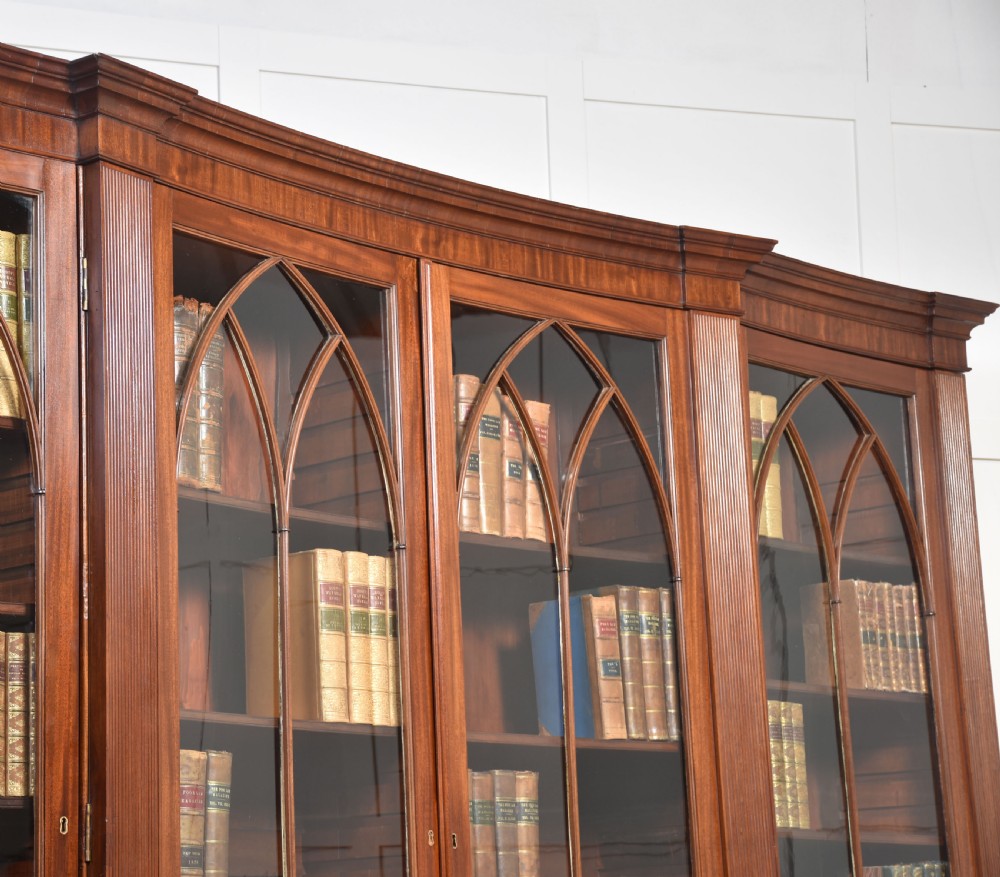 A large Regency mahogany breakfront library bookcase featuring four astragal glazed doors with Gothic arch detailing over four panelled cupboard bases. View XIII