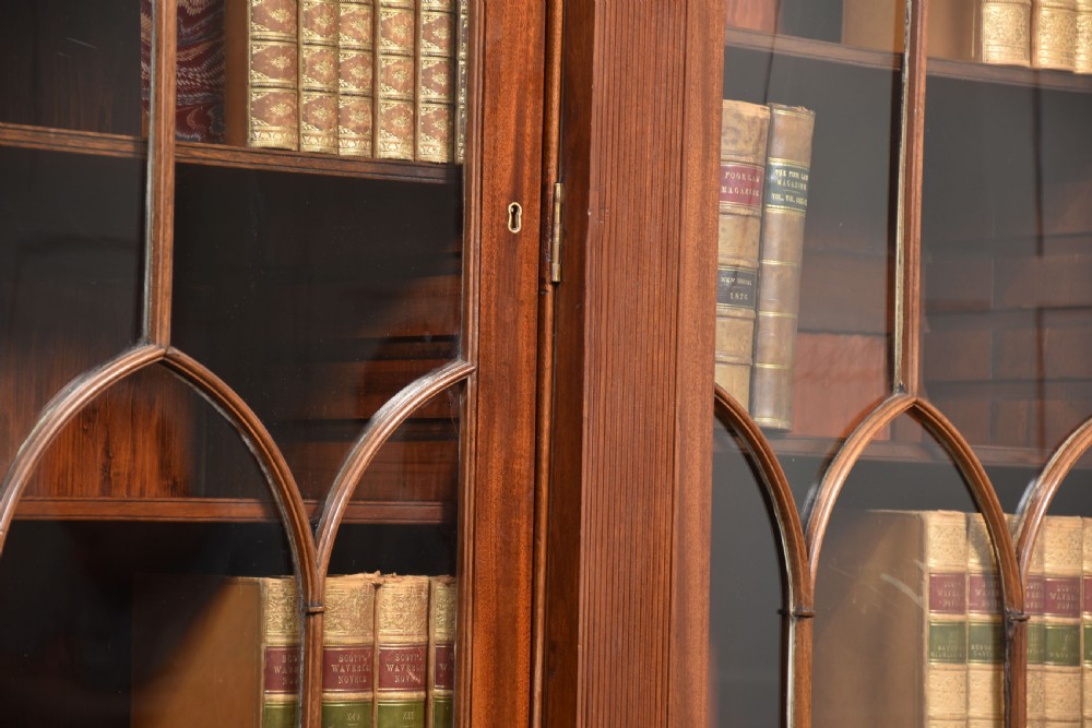 A large Regency mahogany breakfront library bookcase featuring four astragal glazed doors with Gothic arch detailing over four panelled cupboard bases. View XVII