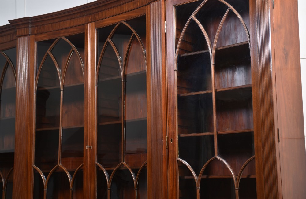 A large Regency mahogany breakfront library bookcase featuring four astragal glazed doors with Gothic arch detailing over four panelled cupboard bases. View XX