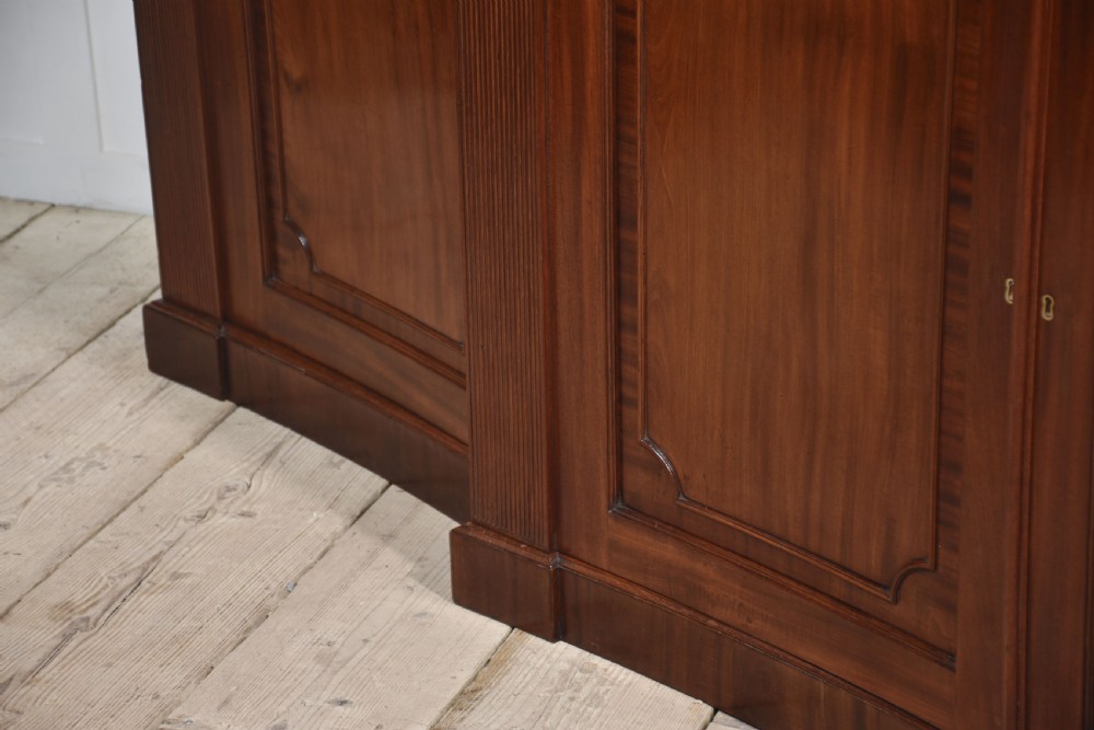 A large Regency mahogany breakfront library bookcase featuring four astragal glazed doors with Gothic arch detailing over four panelled cupboard bases. View XXI