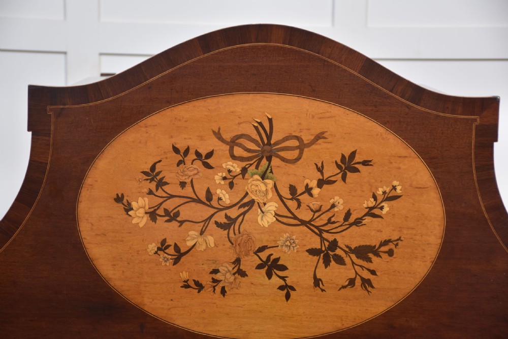 A near pair of bow-fronted mahogany chests of drawers featuring detailed floral marquetry inlay, brass handles, and slender tapered legs. View XV