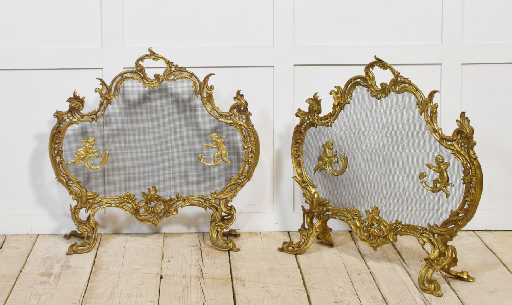 A pair of ornate Louis XV style gilt bronze fire screens featuring Rococo scrollwork, cherub mounts, and wire mesh panels on cabriole feet. View VII