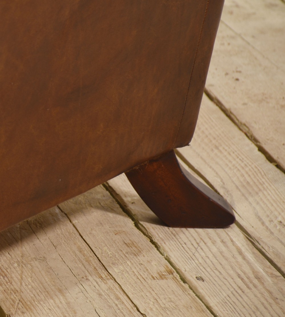 A three-seater brown leather Chesterfield sofa featuring deep buttoned upholstery, rolled arms, brass stud detailing, and turned wooden feet. View XII