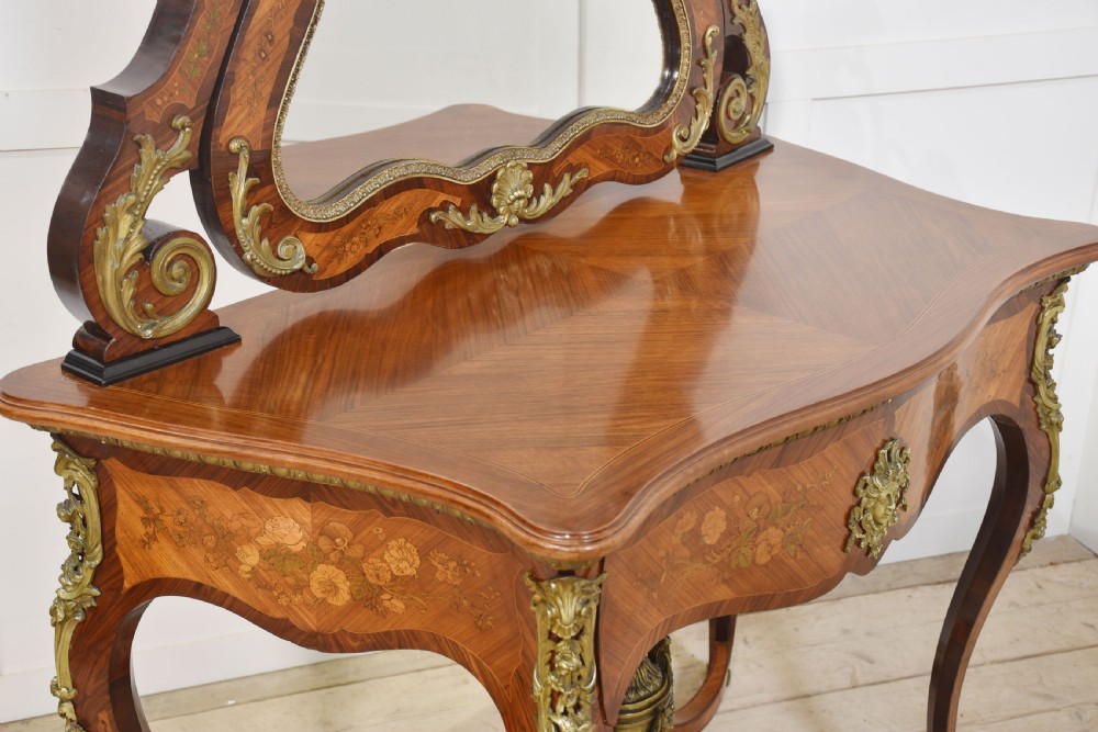 A Louis Philippe tulipwood dressing table featuring floral marquetry inlay, gilt bronze ormolu mounts, a shaped mirror with attached sconces, and cabriole legs. View XVII