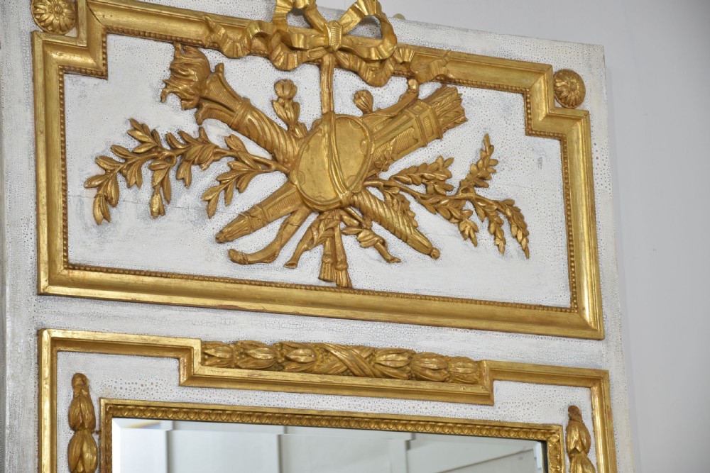 A tall French trumeau wall mirror with a painted white frame, gold leaf parcel gilding, a ribbon cresting top panel, and a rectangular glass mirror. View VIII