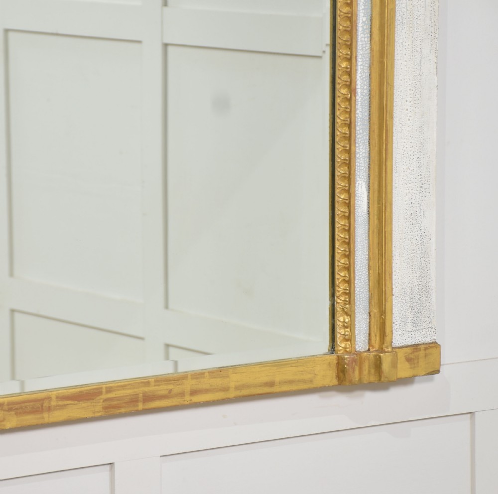 A tall French trumeau wall mirror with a painted white frame, gold leaf parcel gilding, a ribbon cresting top panel, and a rectangular glass mirror. View IX
