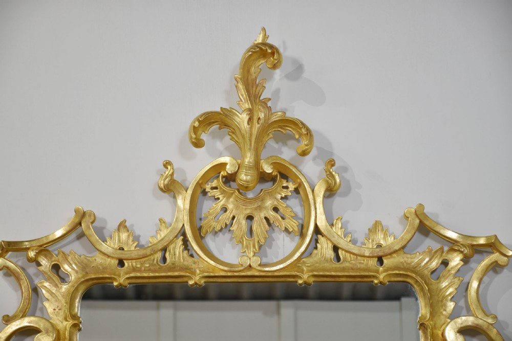 An ornate rectangular Rococo revival wall mirror featuring an elaborate carved giltwood frame with a tall cresting motif, acanthus leaf detailing, and pierced scrollwork. View VII