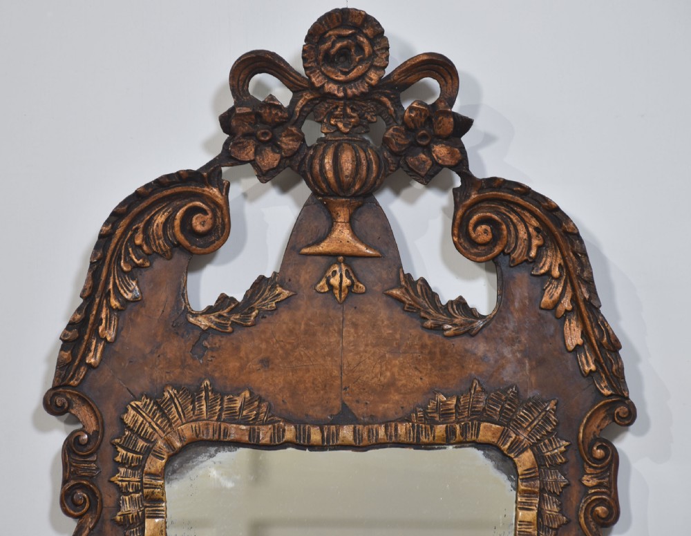 A George II style carved walnut wall mirror featuring a carved floral crest, parcel gilt trim, and a shaped apron surround. View IV
