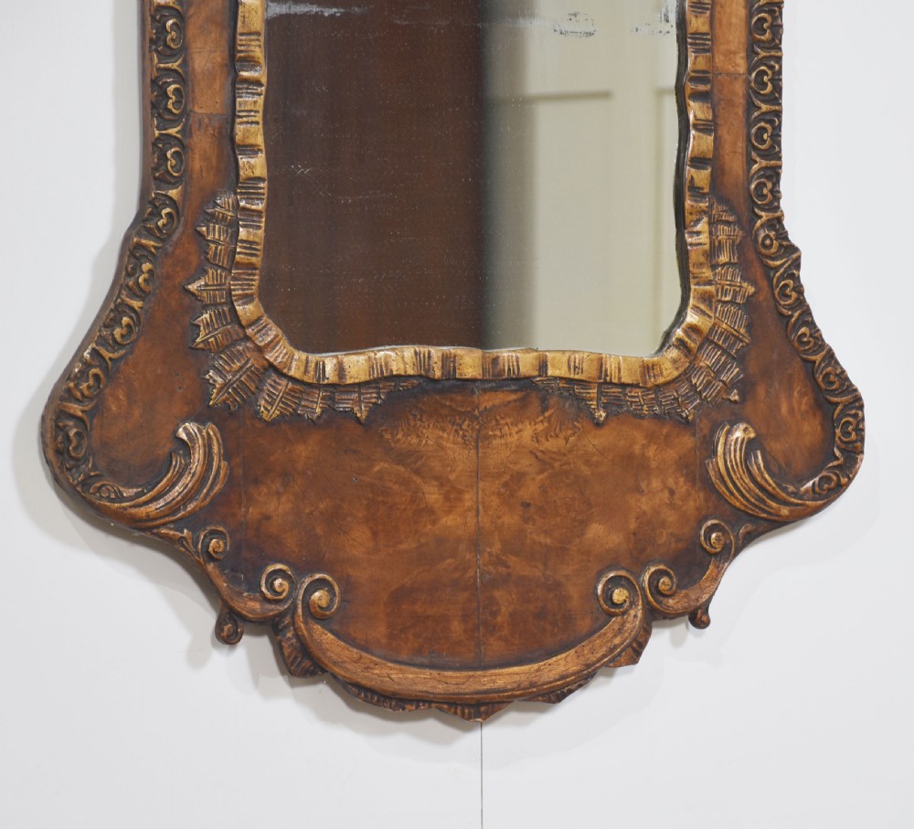 A George II style carved walnut wall mirror featuring a carved floral crest, parcel gilt trim, and a shaped apron surround. View VI
