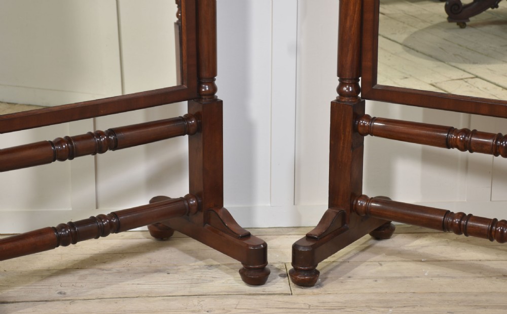 A pair of antique mahogany cheval mirrors featuring rectangular tilting glass plates, turned vertical supports, horizontal stretchers, and brass hardware. View VIII