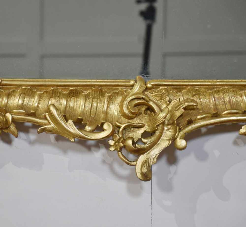 A 19th-century rectangular wall mirror featuring an ornate giltwood frame carved with Rococo C-scrolls and floral motifs. View II