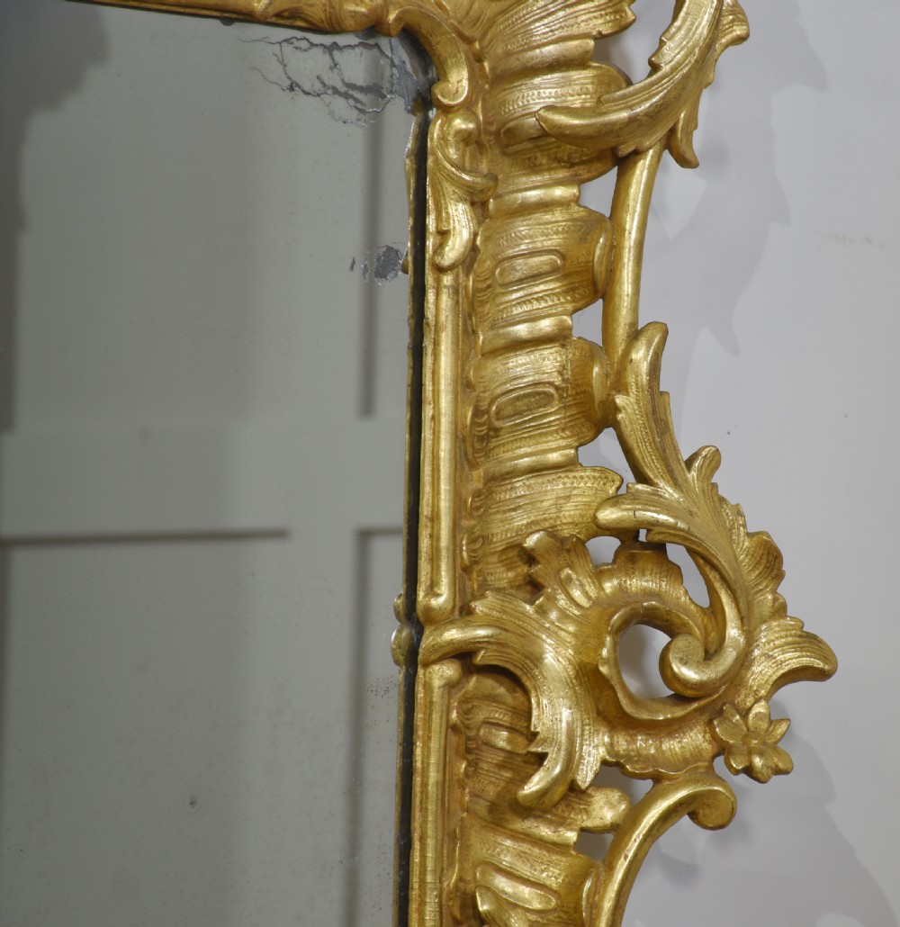 A 19th-century rectangular wall mirror featuring an ornate giltwood frame carved with Rococo C-scrolls and floral motifs. View V