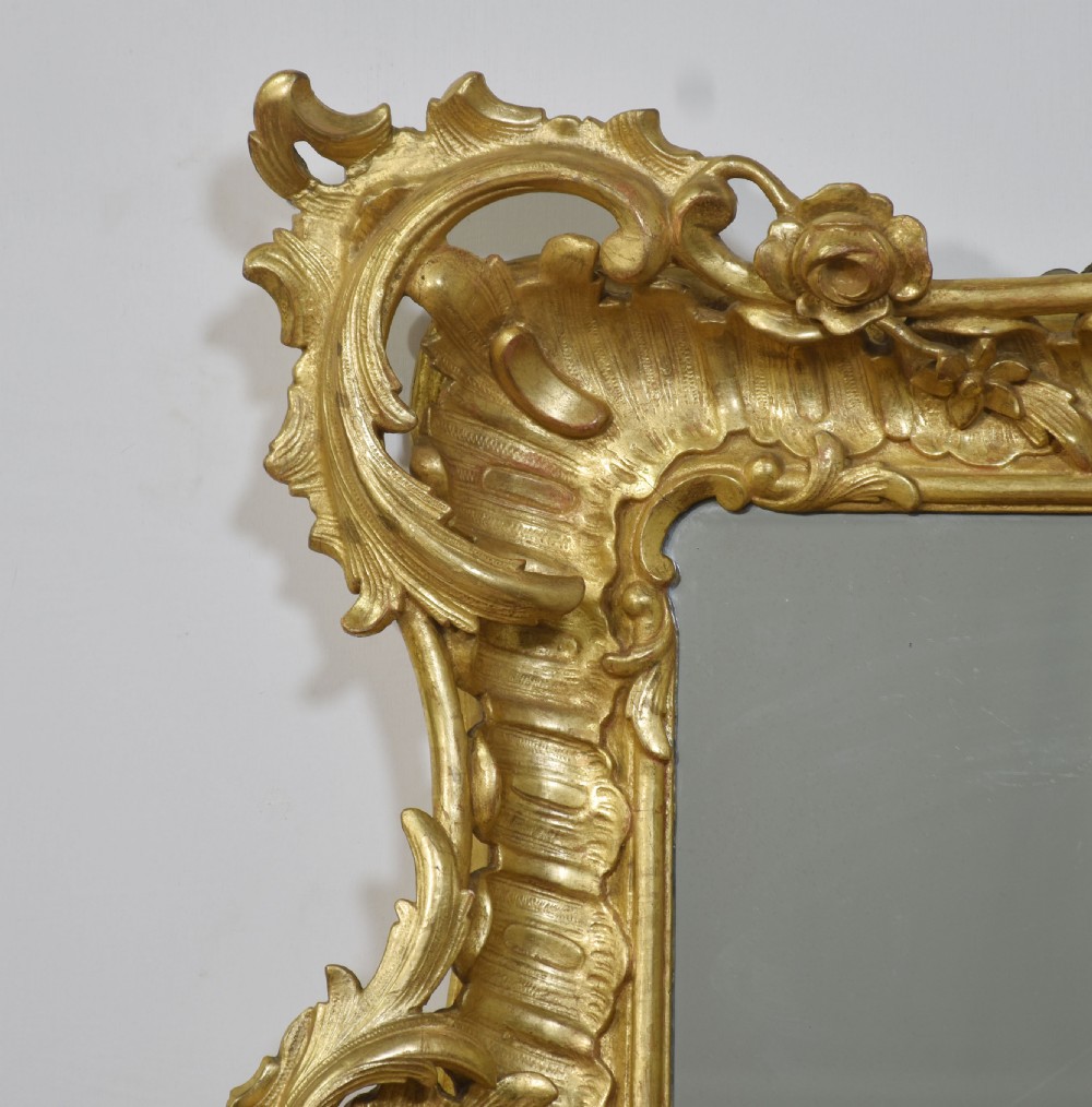 A 19th-century rectangular wall mirror featuring an ornate giltwood frame carved with Rococo C-scrolls and floral motifs. View VI