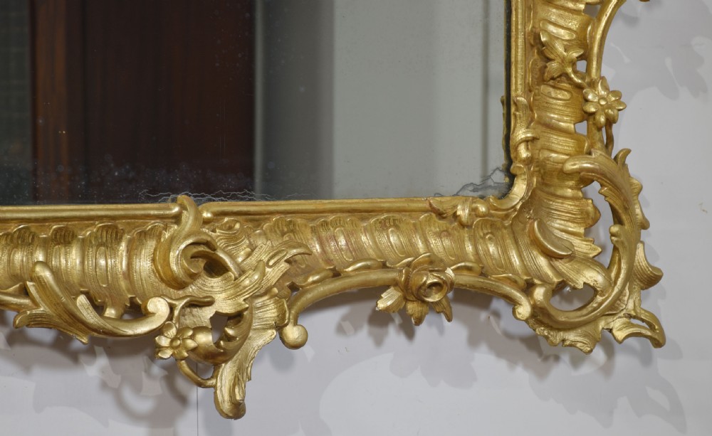 A 19th-century rectangular wall mirror featuring an ornate giltwood frame carved with Rococo C-scrolls and floral motifs. View VII