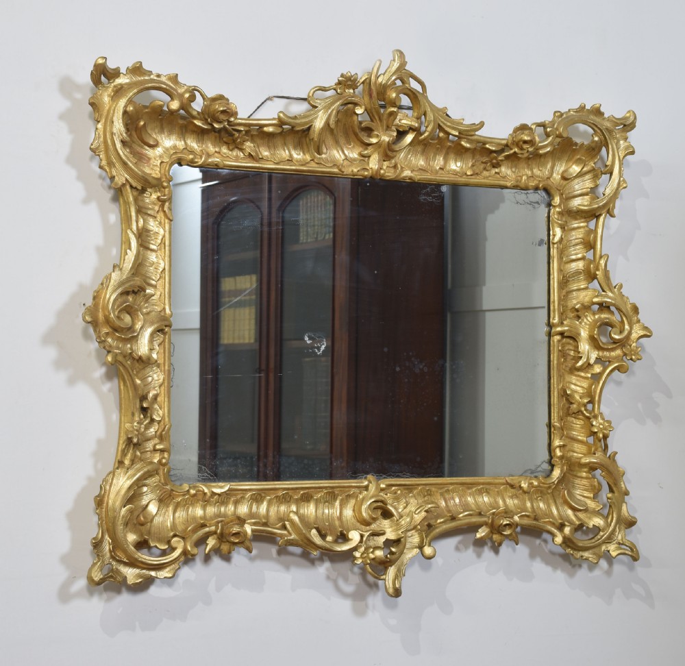 A 19th-century rectangular wall mirror featuring an ornate giltwood frame carved with Rococo C-scrolls and floral motifs. View VIII